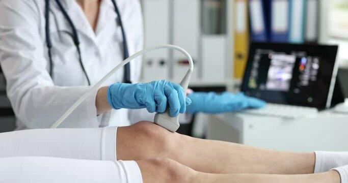 Orthopedic doctor makes ultrasound examination of patient knee in office