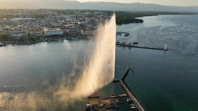 Geneva lake with famous fountain Jet d'Eau at sunset in golden light, symbol of Swiss city of Geneva, view of Geneva harbour with a famous fountain