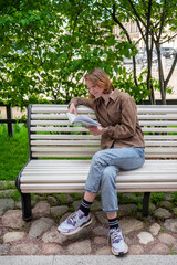 Fototapeta premium girl student reads a book in the park and smiles.
