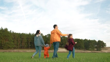 people in the park. happy family a walk at sunset. mom dad and daughter walk holding hands in the park. happy family kid dream concept. parents and fun baby walking forest park life