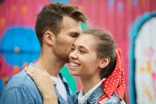 Cropped image of happy dreamy young couple embracing each other against graffiti background