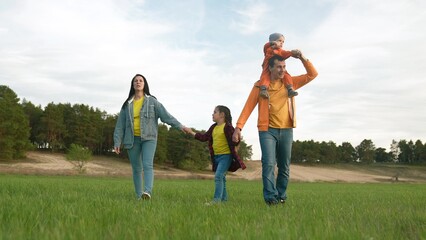 people in the park. happy family a life walk at sunset. mom dad and daughter walk holding hands in the park. happy family kid dream concept. parents and baby fun walking forest park