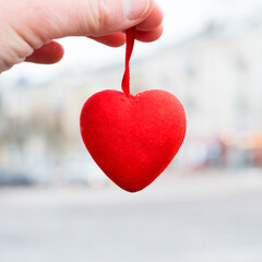 Red heart in hand close-up on the background of the city. Valentine's day preparation concept