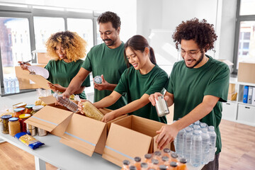 charity, donation and volunteering concept - international group of happy smiling volunteers...