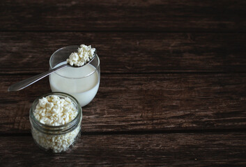 homemade cottage cheese with kefir in a glass glass with a spoon on a wooden background
