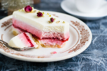 Fruit mousse cake on vintage plate, cup of coffee and decorative christmas tree on gray background.