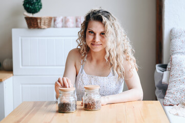 Obraz na płótnie Canvas A curly-haired girl sits in the kitchen near the window, there is a jar of beans on the table