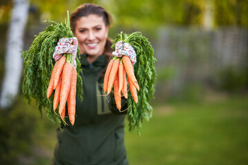 Woman gardener hold fresh carrot in hands