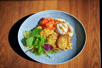 Vegetable zucchini pancakes with poached egg on white plate. Top view