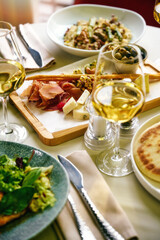 Breakfast served in cafe. Poached egg, tomato, avocado and sauteed spinach on pancakes with salad greens. Glass of sparkling wine.