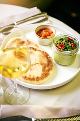 Breakfast served in cafe. Poached egg, tomato, avocado and sauteed spinach on pancakes with salad greens. Glass of sparkling wine.