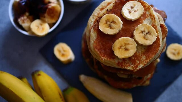 Personne qui mange une tranche de banane sur un tas de pancakes  