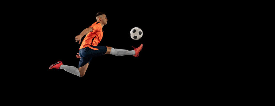 Flyer. Dynamic portrait of professional male football soccer player in motion isolated on dark background. Concept of sport, goals, competition, hobby, achievements