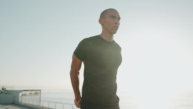 Handsome bald sportsman wearing black t-shirt does hands warm-up outdoors in the morning