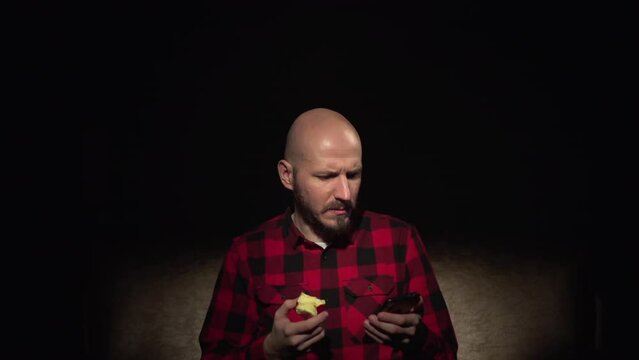 Caucasian young bald hipster man with beard eat apple