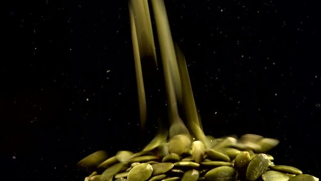 Pumpkin seeds are pouring on a black background.