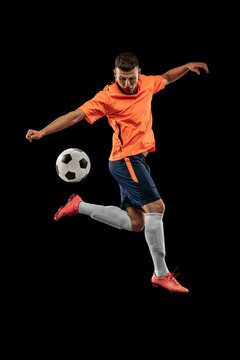 Studio shot of professional male football soccer player in motion isolated on dark background. Concept of sport, goals, competition, hobby, achievements