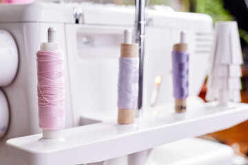Sewing spools on a white overlock sewing machine close-up
