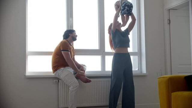 Happy family with little baby son near the windowsill