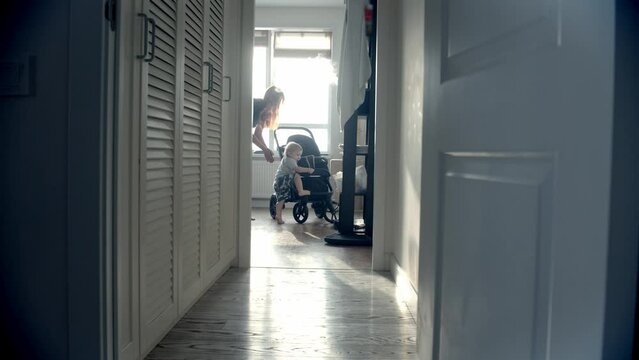 A small baby tries to climb into his stroller and his