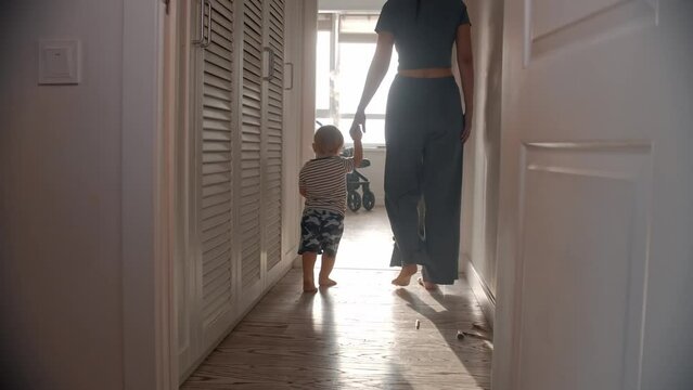 A little baby walking with his mom in the apartment