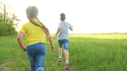 Fototapeta premium people in park. happy family children a kid together run in park at sunset silhouette. brother and sister run. happy family children running summer. kid dream concept. fun children run