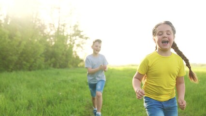 Naklejka premium catch-up. children kid dream together run in the park at sunset. happy family people in park concept. boy and girl playing run. baby child running in green meadow. happy family kid fun dream concept