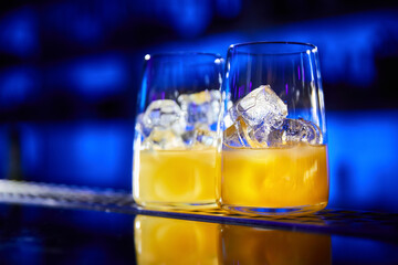 The process of preparing alcoholic cocktails. Glasses with ice cubes and juice on the bar