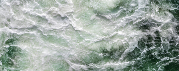 Close-up abstract texture above view of river torrent and clear fresh cold water flowing through...