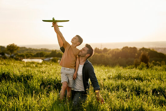 Little boy with father playing a toy airplane at meadow