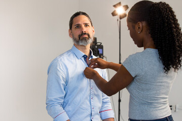 Putting Lavalier Microphone on Caucasian Male Wearing Business Attire. Video Production or Film Set...
