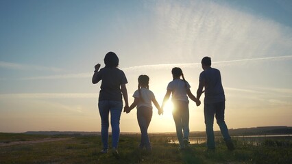 happy family silhouette. group of people family a holding hands walking at sunset by the water on...