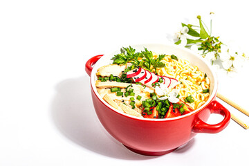 Asian noodles with chicken, vegetables, and herbs are isolated on a white background
