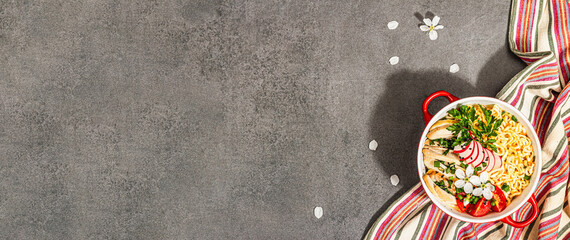 Asian noodles with chicken, vegetables, and herbs in a red bowl. Traditional Japanese soup