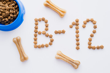 top view of word made of dry pet food near bowl and bone shaped treats on white.