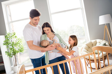 Portrait of full idyllic peaceful family embrace hands hold newborn baby enjoy weekend house indoors