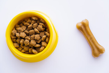 Fototapeta na wymiar top view of yellow plastic bowl with pet food near dog treat isolated on white.