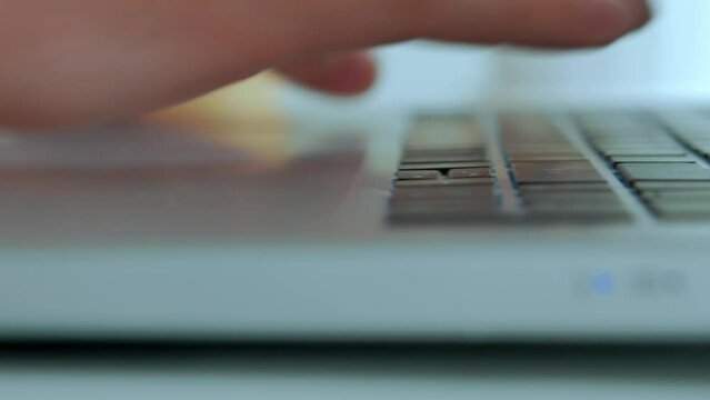 A close -up, male hands hit the keyboard of a laptop, print a text, a selective focus.