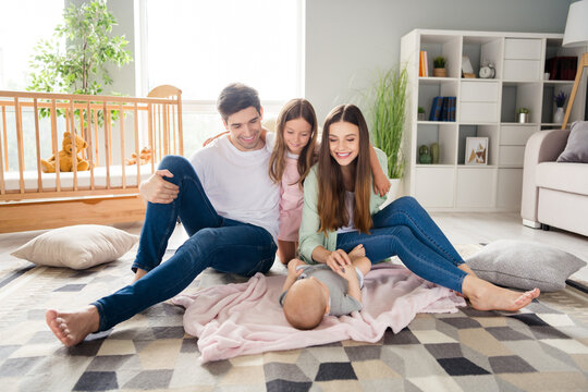 Photo of funny charming husband wife two children sitting floor spending time together smiling indoors room home house