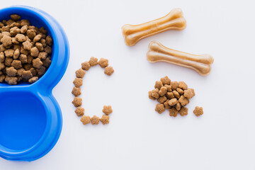 Fototapeta premium top view of bone shaped pet treats near pet food and letter isolated on white.