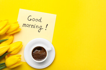 Cup of aromatic coffee, beautiful tulips and Good Morning note on yellow background, flat lay....