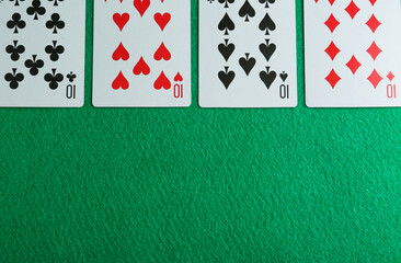 Playing cards with four of kind combination on green table, flat lay. Space for text