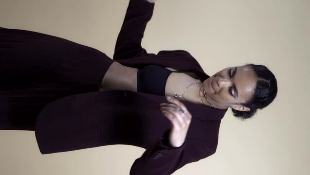 stylish african american woman taking off black blazer isolated on grey