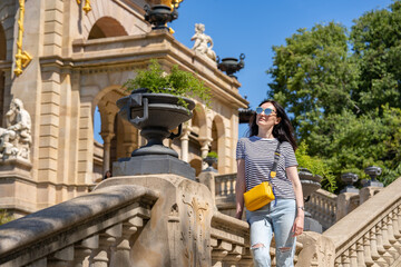 Young 30 years old woman in jeans, t-shirt and yellow bag walking in a park Ciutadella in...