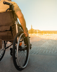 Hombre mayor discapacitado, en el parque en día soleado, sentado en la silla de ruedas. Fotografía vertical con espacio para texto. - obrazy, fototapety, plakaty