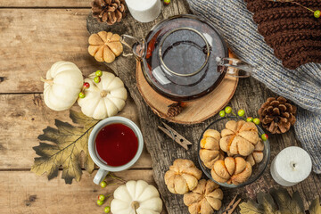 Autumn tea concept. Cookies with pumpkin puree, black tea in a glass teapot, fall decor