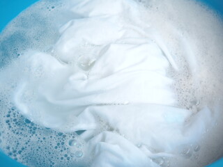 Shirt washing with detergent bubble in wash tub. top view  photo, blurred.
