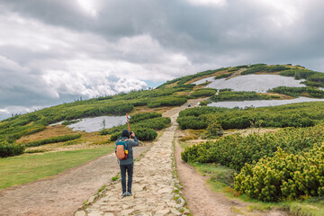 Obraz premium Male hiker with backpack on top of mountain. Man in sportswear takes a photo of a mountain. Babia Góra Poland. 