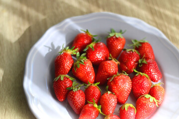 Lilac plate full of fresh strawberries on wooden table. Selective focus.