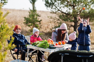 Obraz premium Cheerful mother with kids at a picnic. Family on vacation with fruits outdoor.